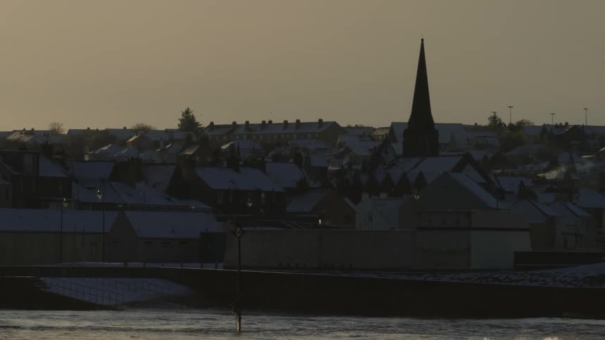 Waves crash against the shore of the town