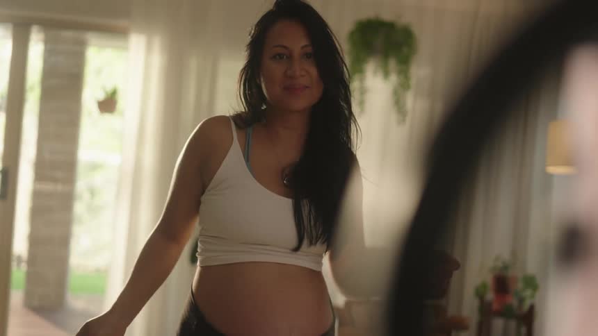 Pregnant woman dancing in front of a smartphone on a tripod