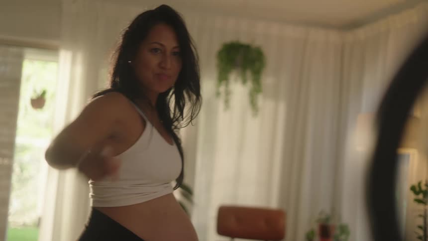 Woman dancing barefoot in front of a smartphone on a tripod in a living room