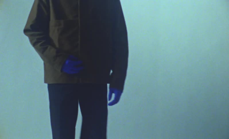 Person in a black coat and pants posing in a studio