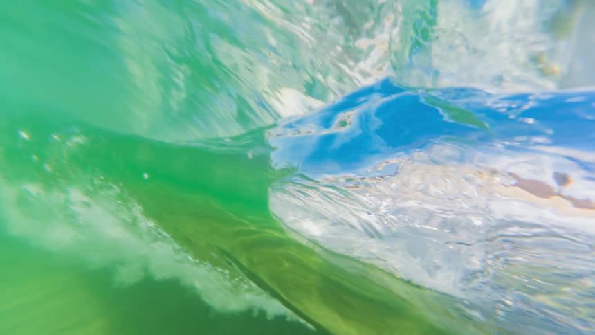 Underwater view of clear ocean water with a breaking wave
