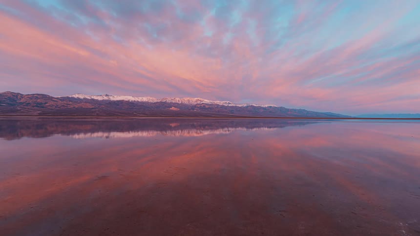The clouds reflect in the water by the mountain