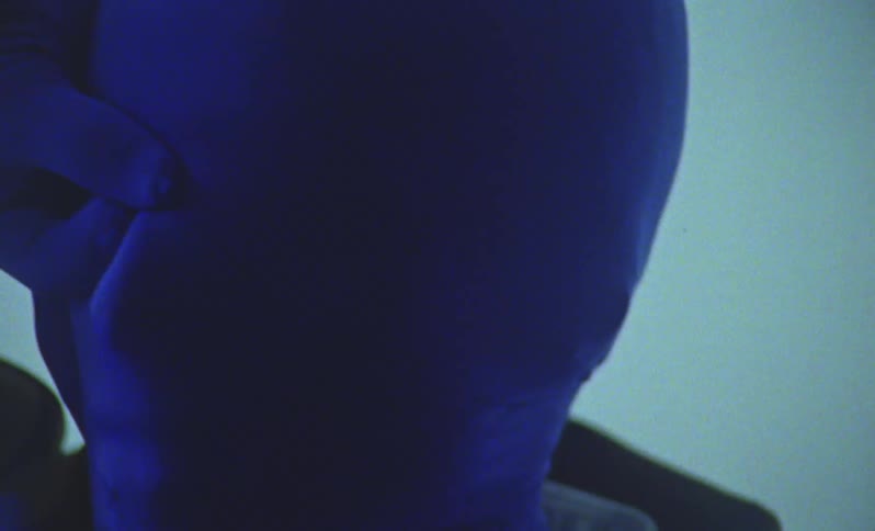 Closeup of a person wearing a blue mask and gloves gesturing for the camera during a photo session in a studio