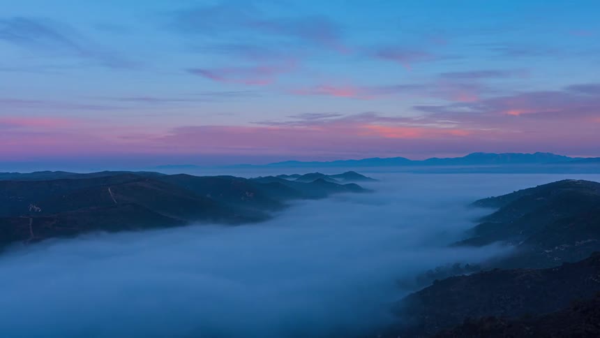 Landscape of a sea of low clouds on mountains with the sky with a mix of blue and pink colors