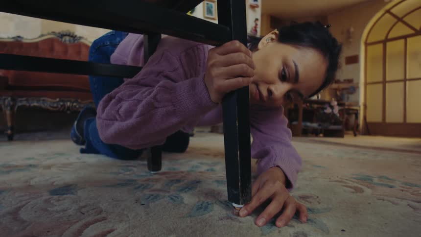 Woman balances a wobbly piece of furniture by placing stacked coins under one of its legs