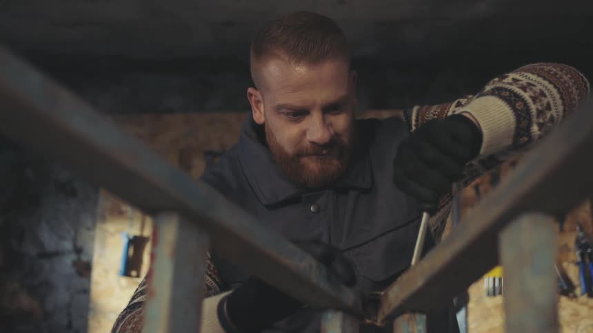 Man making an effort expression while screwing a wooden slat