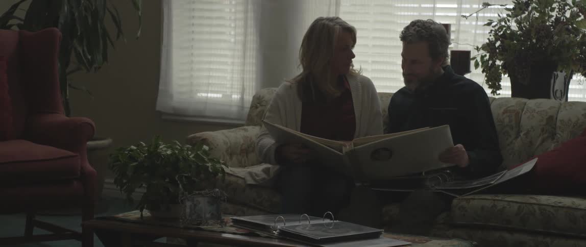 A man and woman sit on a couch browsing photo albums