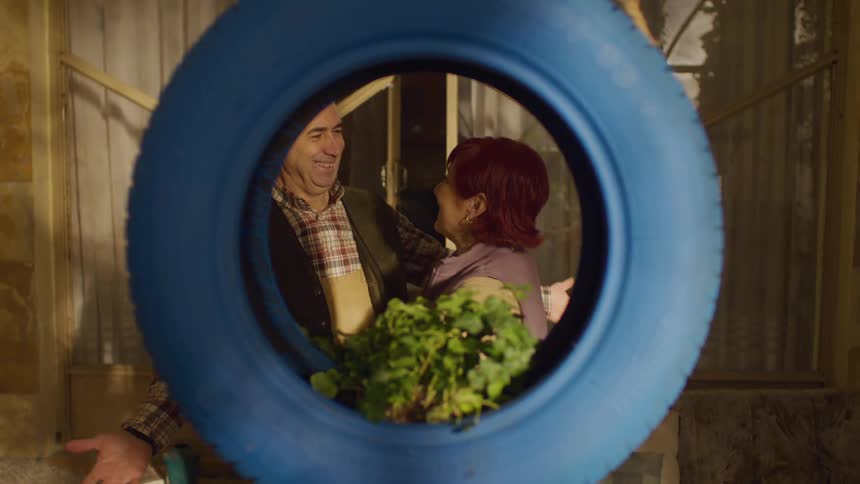 Man surprising his wife with a blue tire with a flower seedling