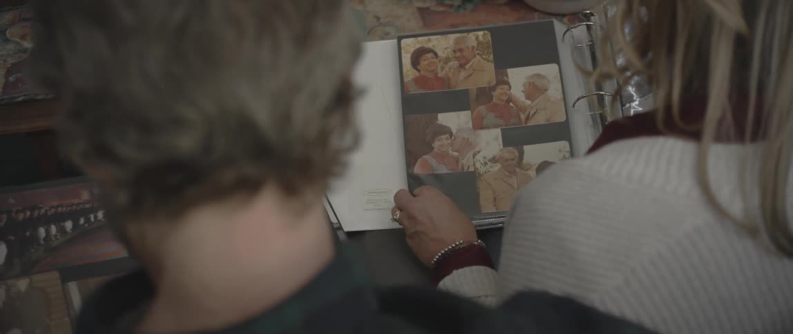 A man and woman sit and browse through photo albums