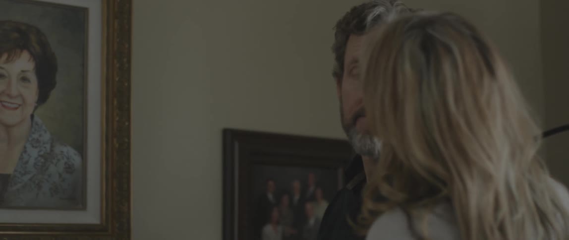 Man and woman look at a framed painting of a woman