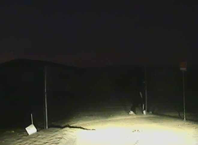 Person opening a gate in a deserted location at night