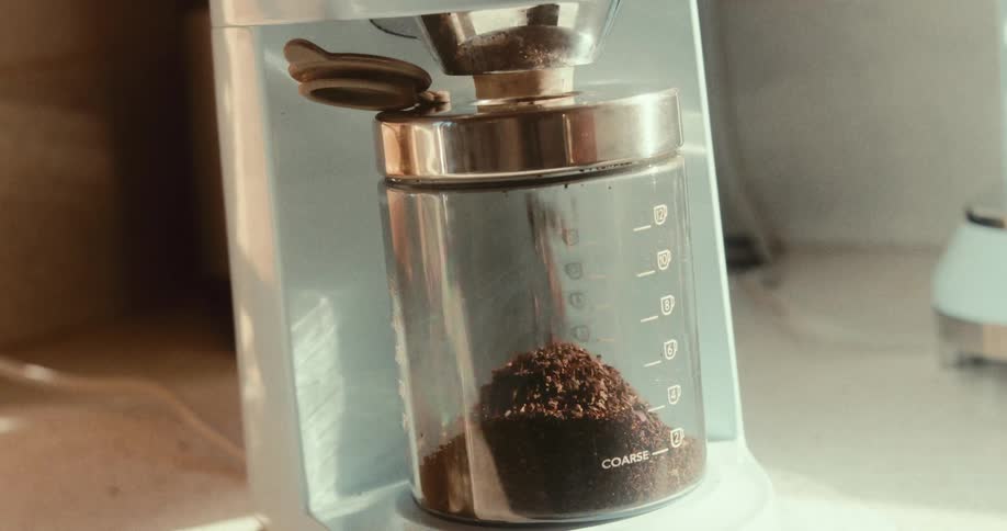 Ground coffee powder being poured into a glass jar