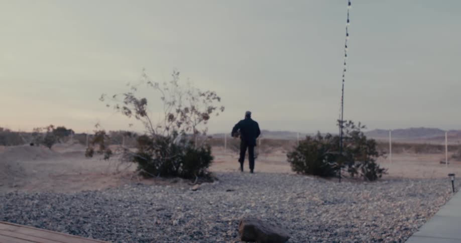 Man walking in a desert area with low vegetation