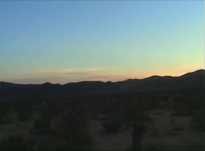Landscape of a field with the silhouette of mountains and the dawn sun