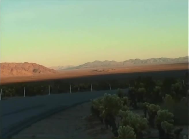 A sunlit mountain range dominates the landscape under a clear sky with a dark silhouetted foreground