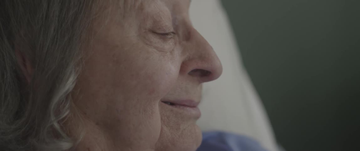 An elderly woman smiles in bed