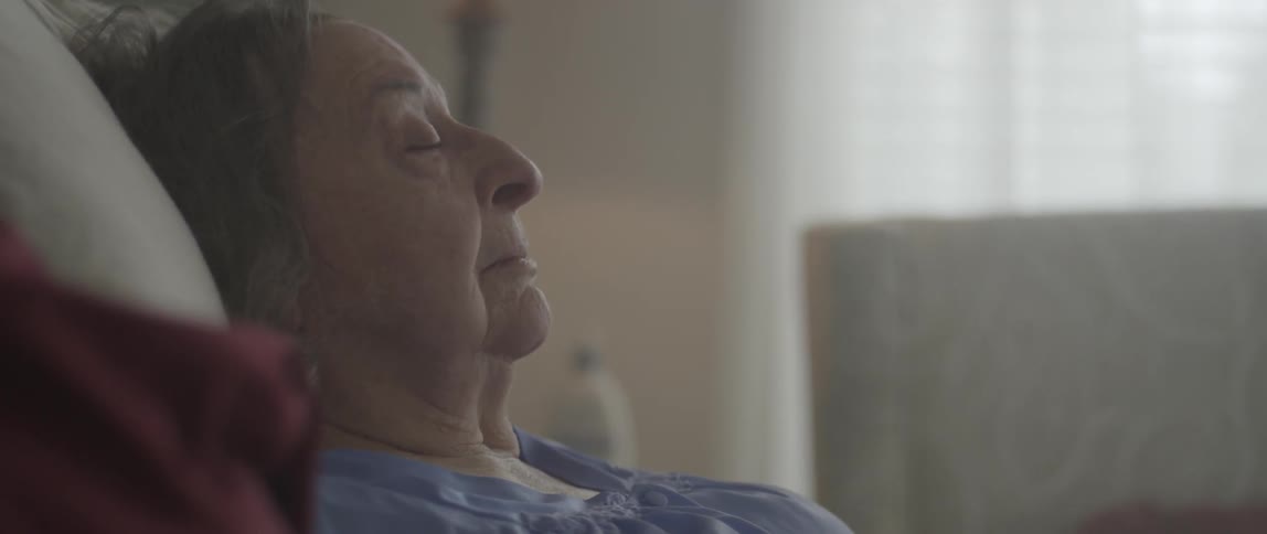 An elderly woman sleeps in bed
