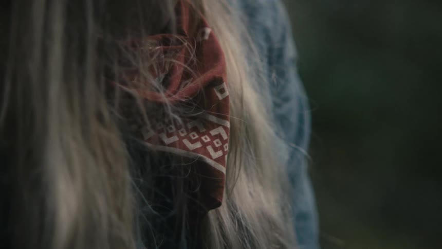 A red bandana around the neck of a person with long blond hair