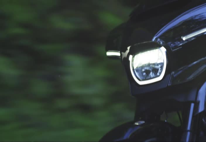 A black motorcycle headlight with its light on in motion