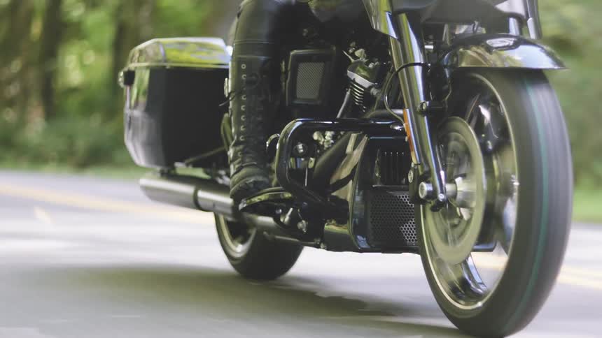 Motorcyclist rides a motorcycle along a highway during a sunny day