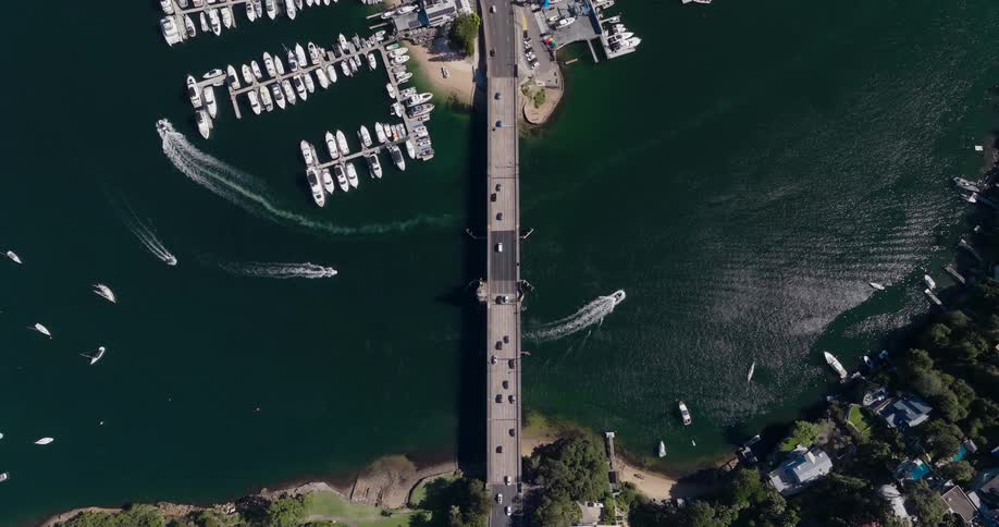 Traffic crosses the bridge between a residential neighborhood and the marina while boats move under the bridge