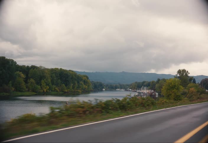 A view of a river with banks full of green vegetation and an asphalt road on the right side
