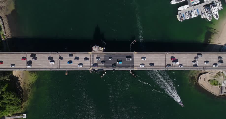 An aerial view of a bridge passing over a body of water with several vehicles passing over it