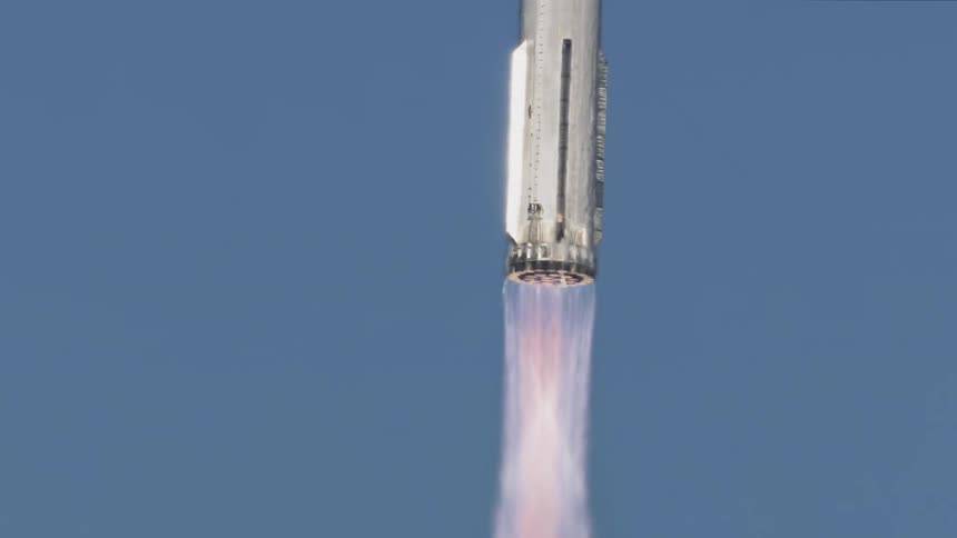 A rocket ascends against a clear blue sky flames billowing from its base shortly after liftoff