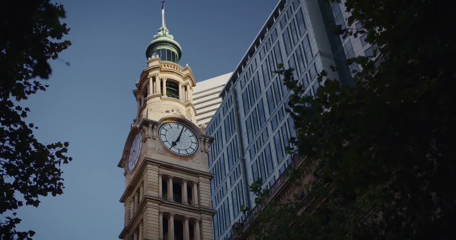 A historic clock tower with a spire against a modern high rise building