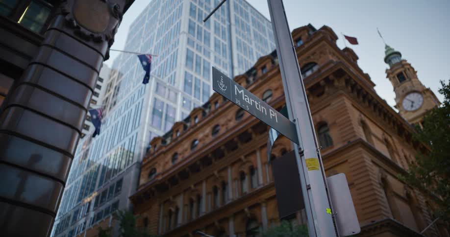 Street sign for martin pl is mounted on a metal pole with a historic brownstone and a mirrored skyscraper in the background
