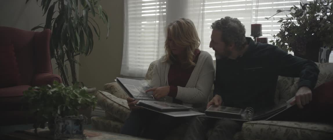 A man and woman sit on a couch browsing photo albums