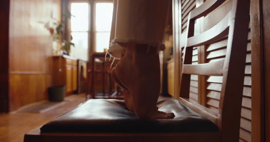 Woman on tiptoe on top of a chair going down