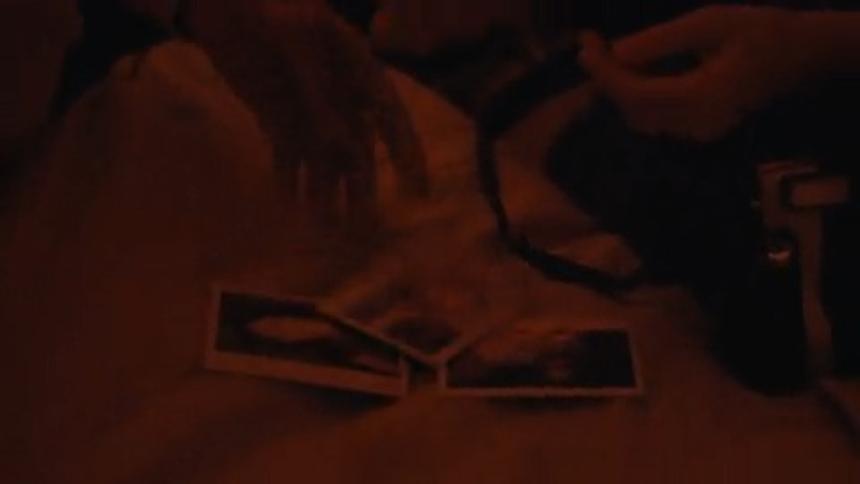 Female photographer and a man look through photographs in a dimly lit room
