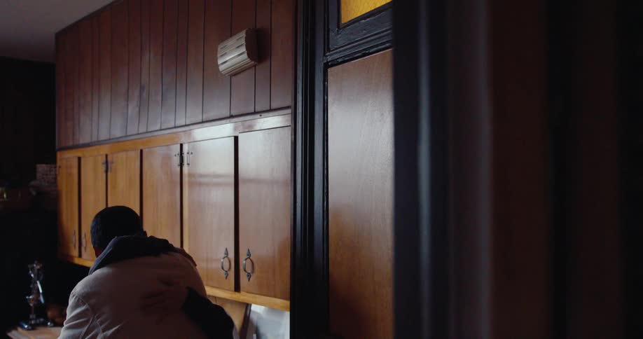 A man and a woman talking in a wooden indoor environment and then they hug and the man leaves through the door