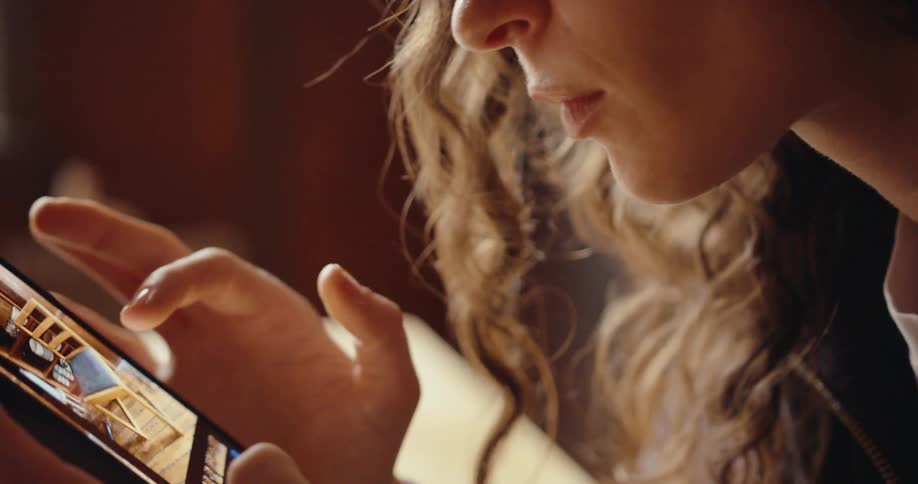 The face of a young woman who is intently looking at her cell phone screen as she is scrolling through images