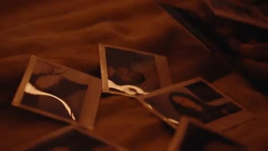 Man and woman cuddle and look at photographs while on their bed