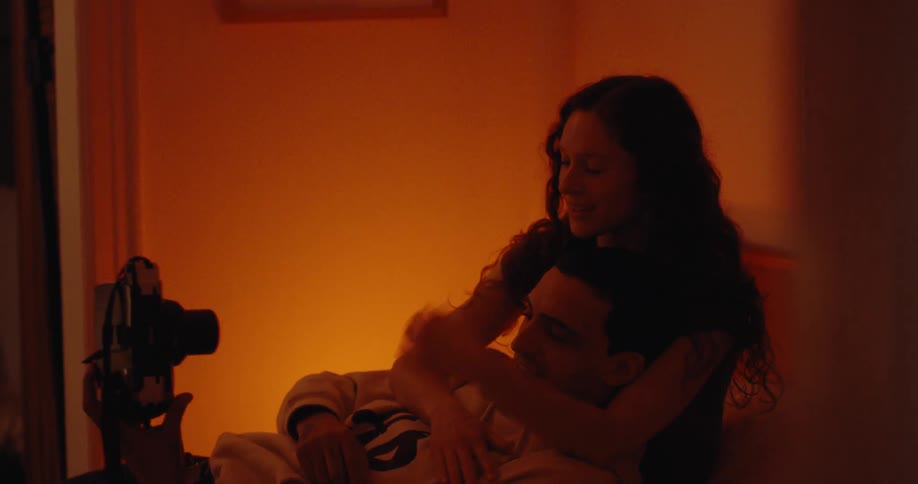 Couple takes a picture of themselves while lying on a bed cuddling