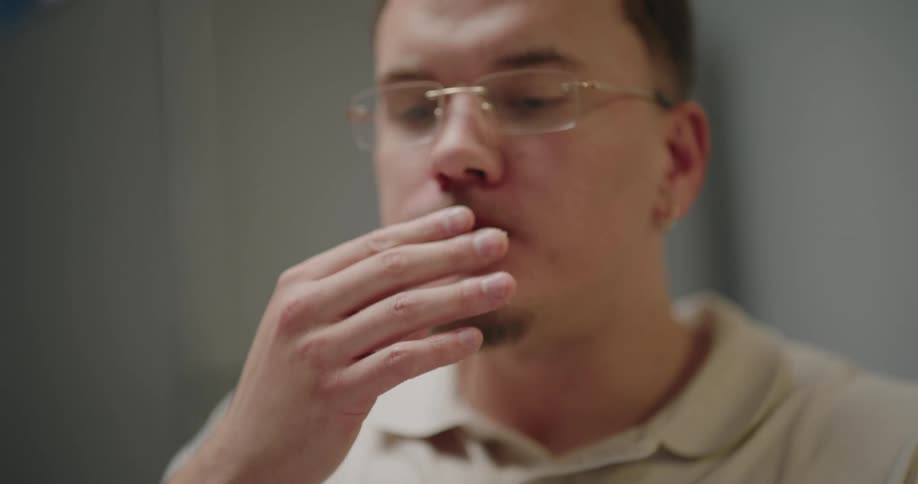 Man with glasses and gold earring bites into a sugarcoated candy