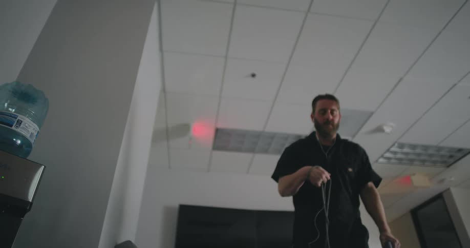 A man is vacuuming the lobby of the office while listening to music