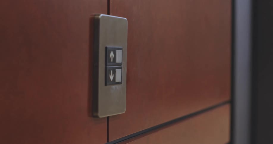 A man presses the button on the elevator and gets on