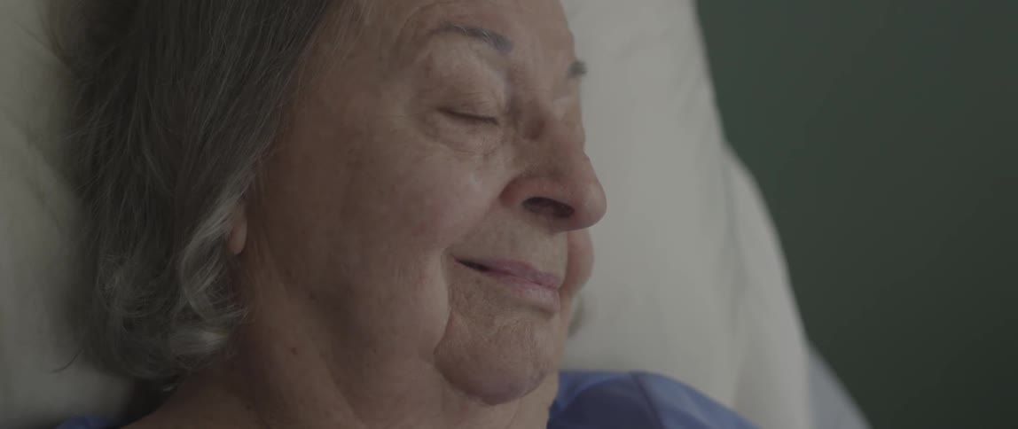 An older woman smiles and falls asleep