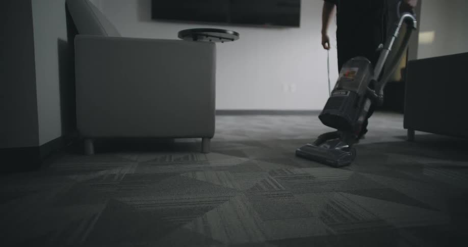 Person vacuuming a carpet in the living room