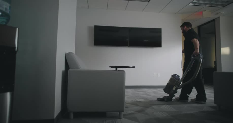 Man vacuuming a carpet in an office room
