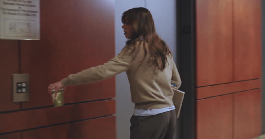 A woman walks down the hall and enters the elevator