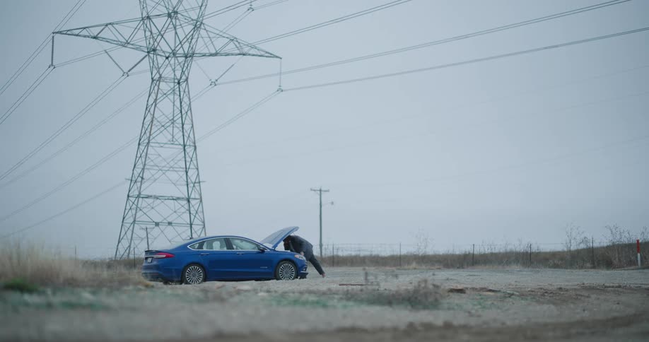 Man having car trouble in the rural countryside makes a phone call