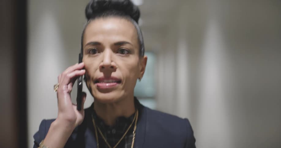 Woman answering a phone call while walking down an office hallway