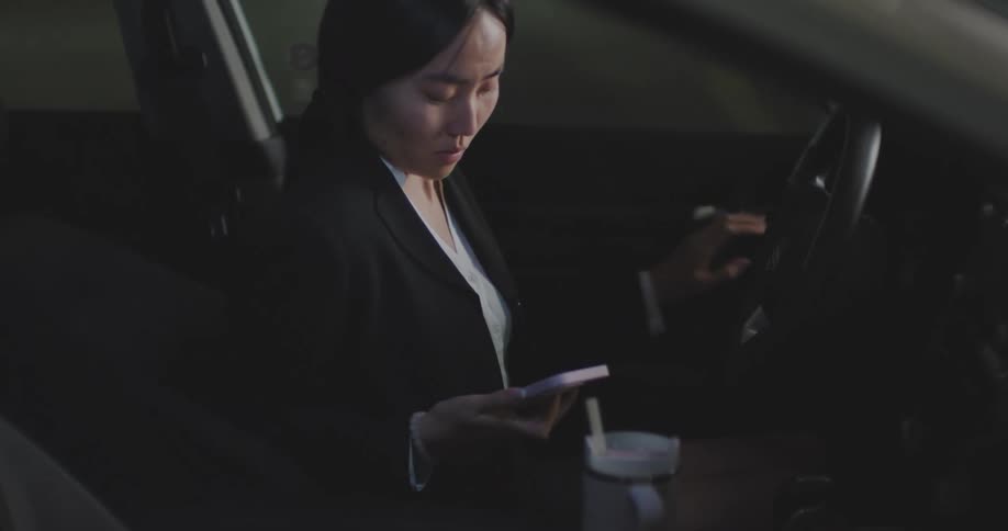 Woman taking a nap in her car is woken by her phone alarm and exits the car