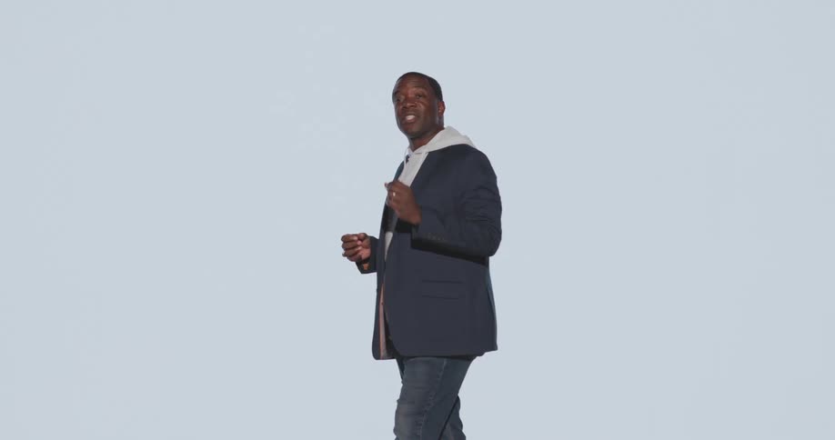 A man in a blazer over a hoodie is presenting while bright camera flashes illuminate him creating an overexposed effect