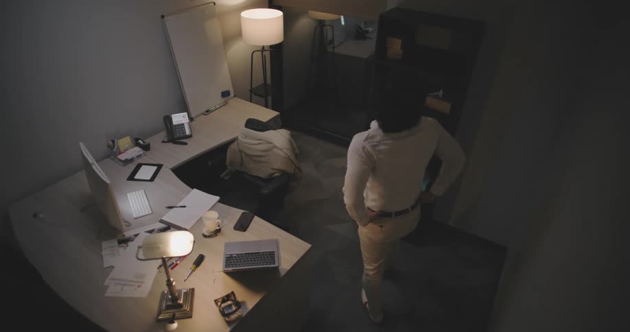 Man getting up from his office desk chair and pacing back and forth across the room