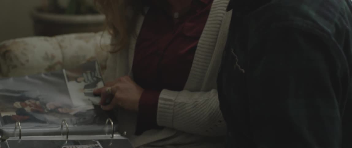 A man and woman look at a photo album on a couch